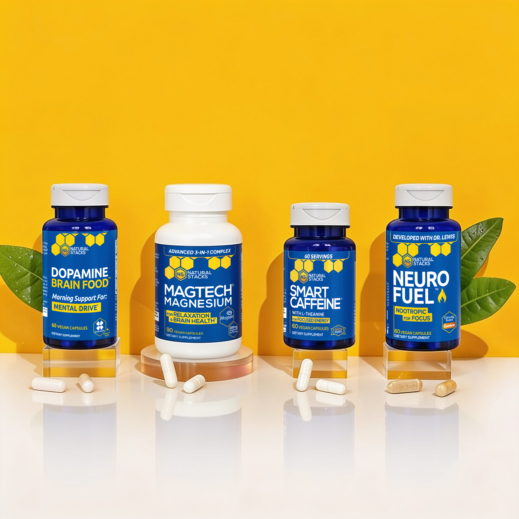 four supplement bottles on stands with yellow background and tablets on table
