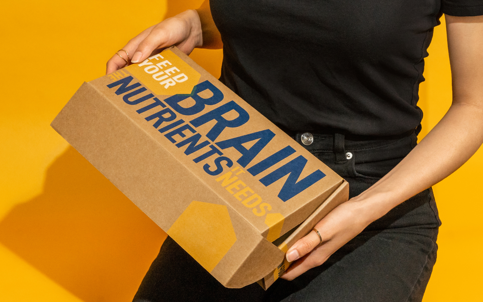 Female holding a box that says - Feed your brain the nutrients it needs