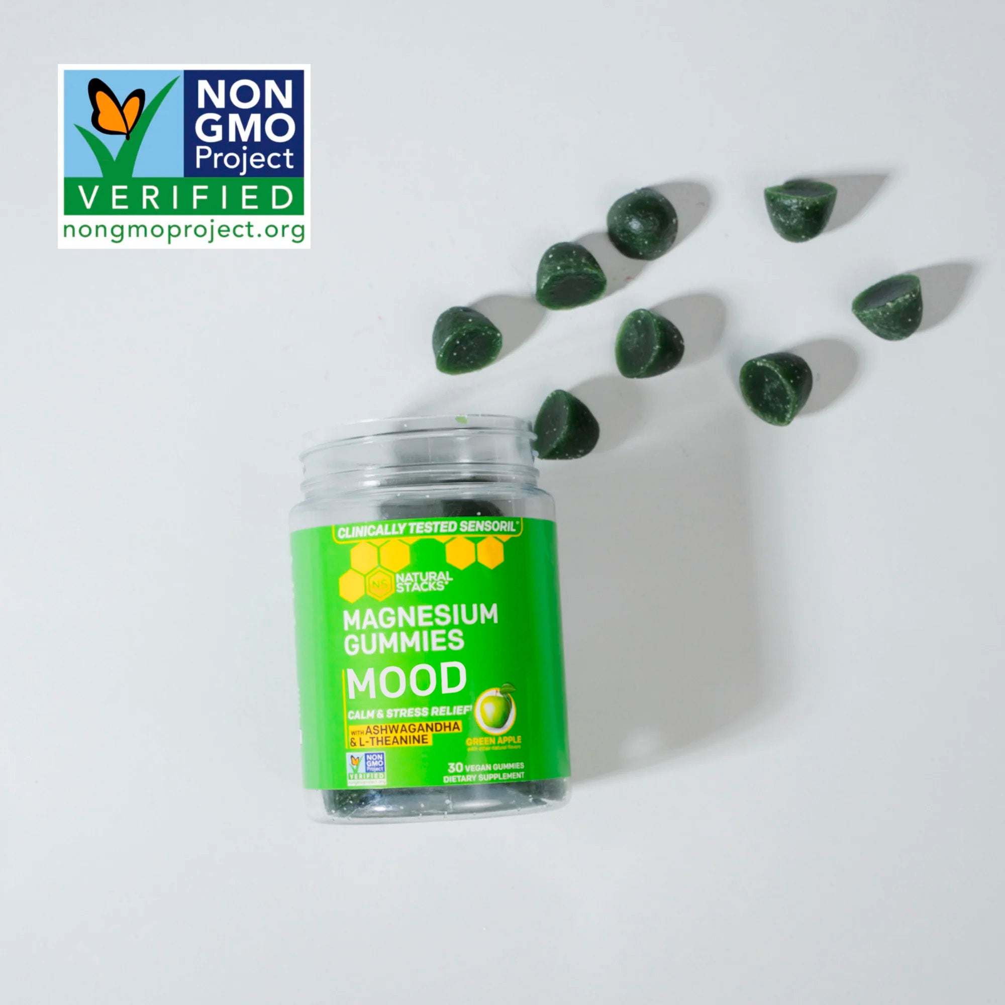 Jar of magnesium gummies with scattered gummies on a white background, featuring Non-GMO Project verification.
