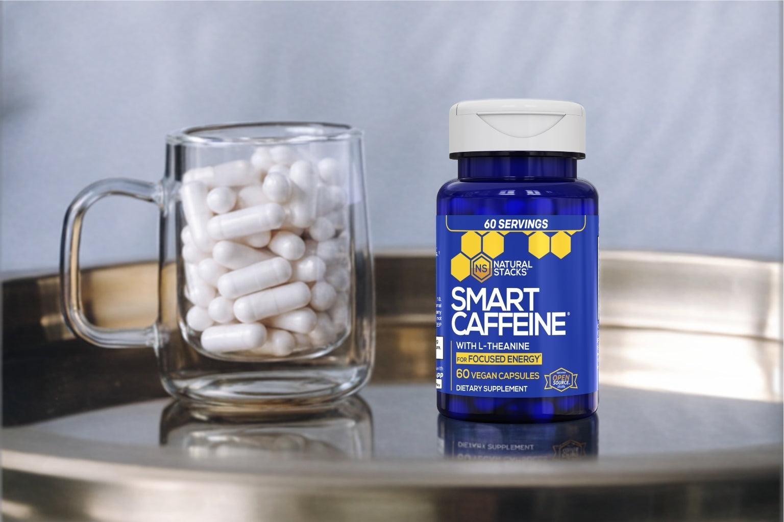 Smart Caffeine supplement bottle with a glass mug filled with capsules on a reflective surface.