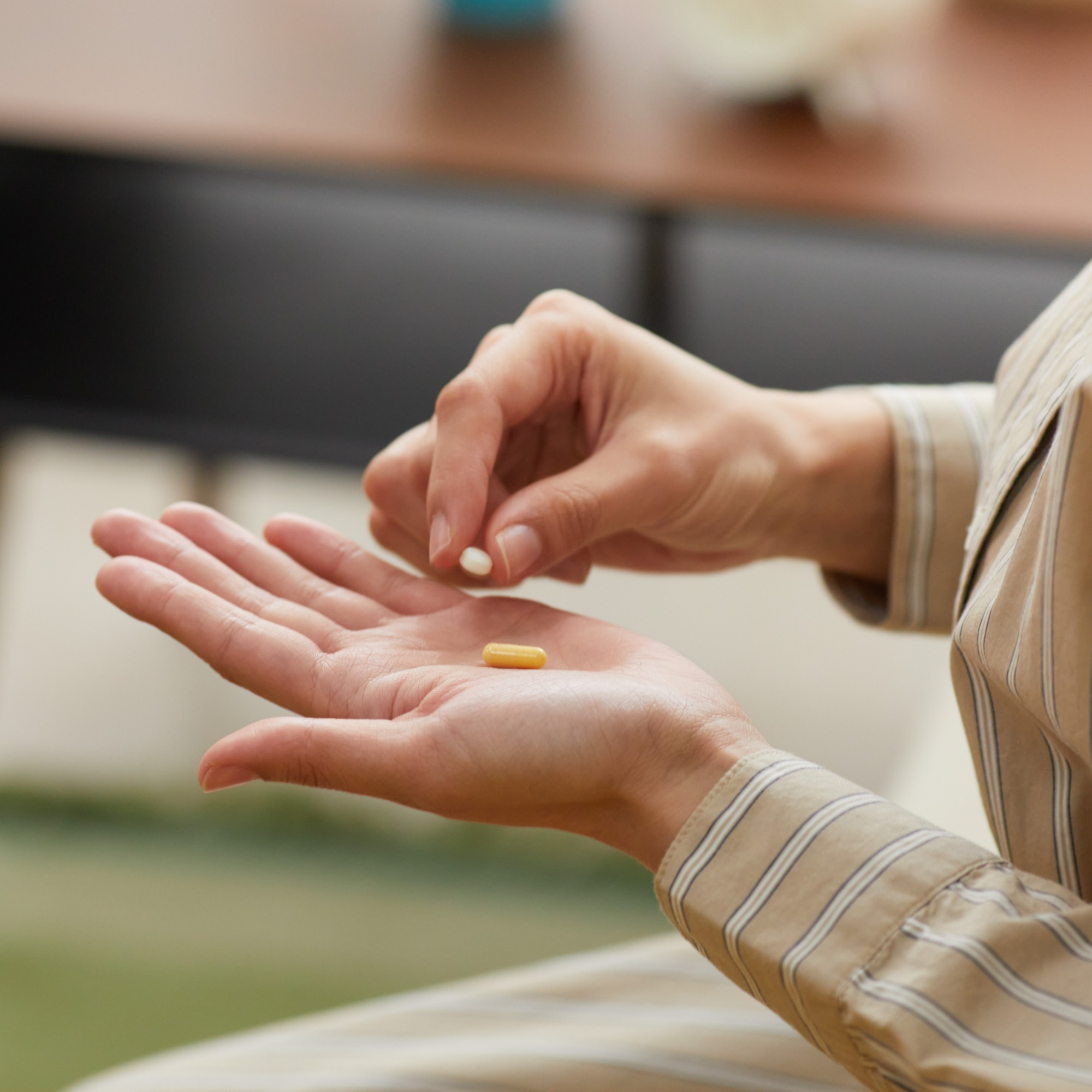 Person holding a yellow pill in their hand