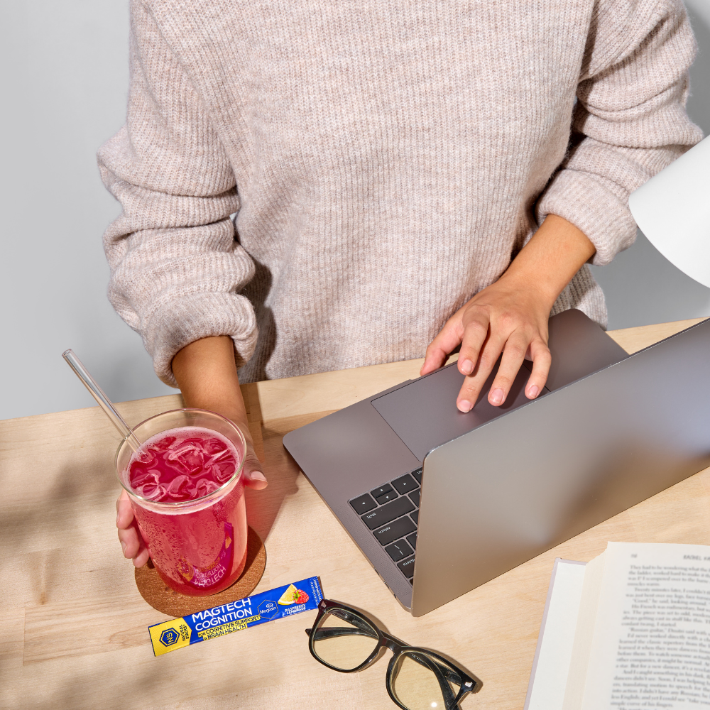 Person using a laptop with a pink drink