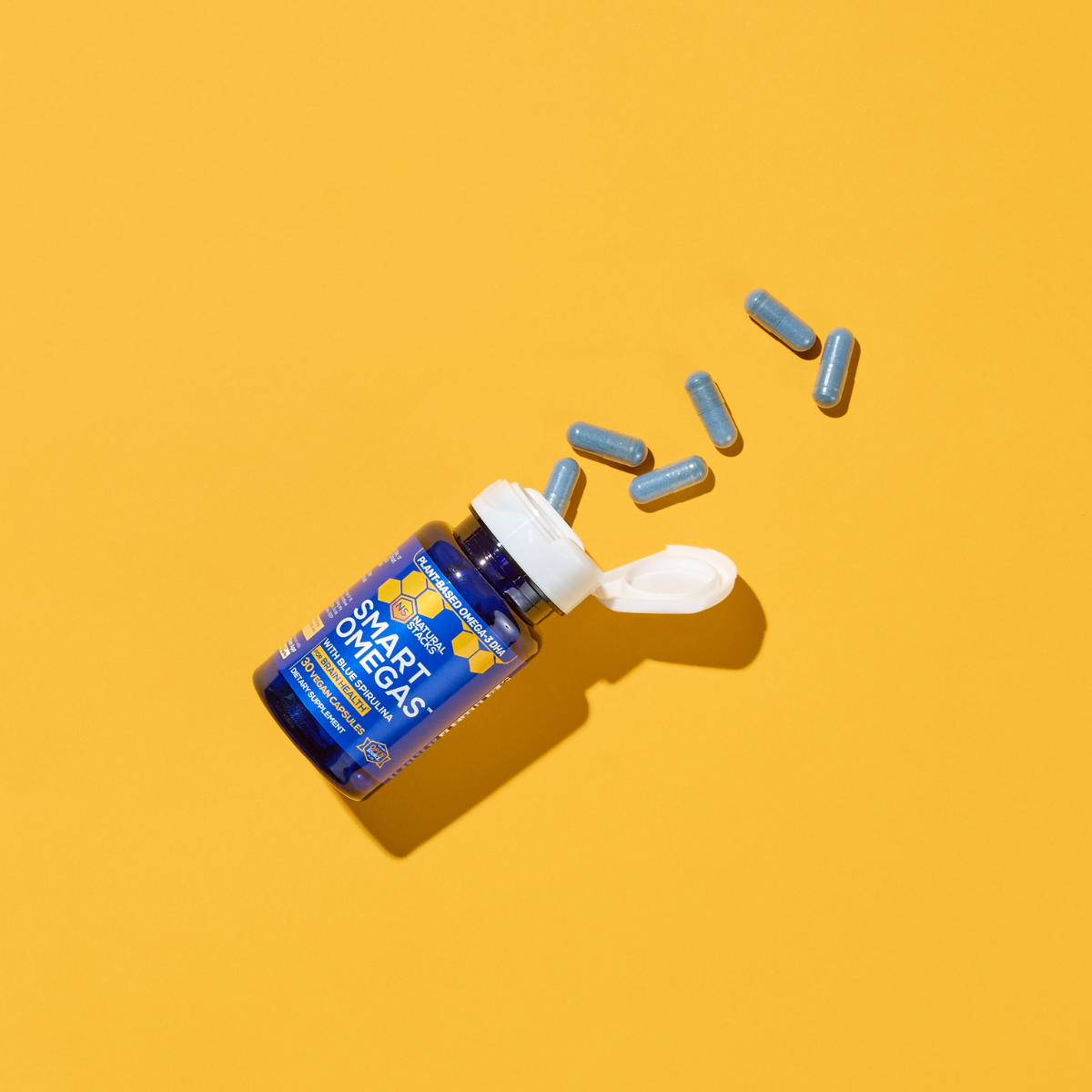 Omega-3 supplement bottle with capsules on a yellow background