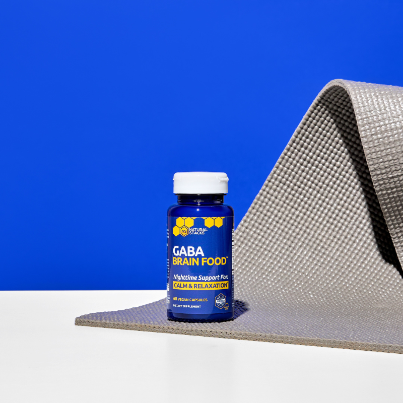 Bottle of GABA Brain Food supplement on a textured surface with a blue background