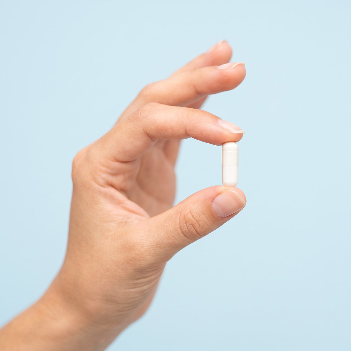 A single mixed-berry sleep gummy held between finger and thumb