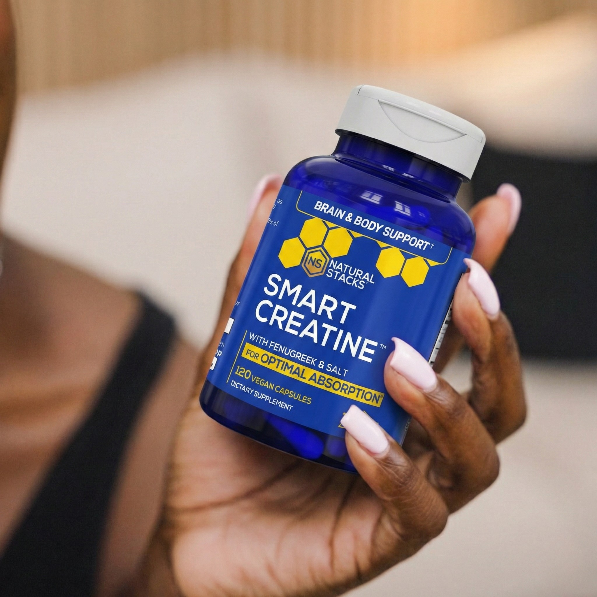 Hand holding a blue supplement bottle labeled 'Smart Creatine' with a blurred background
