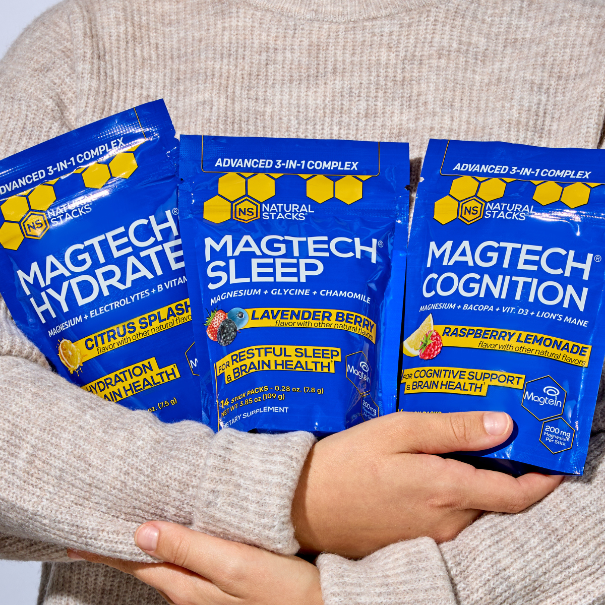 Three packages of Magtech supplements held by a person wearing a gray sweater.
