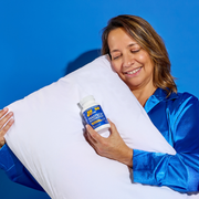 Woman holding a supplement with a pillow against a blue background